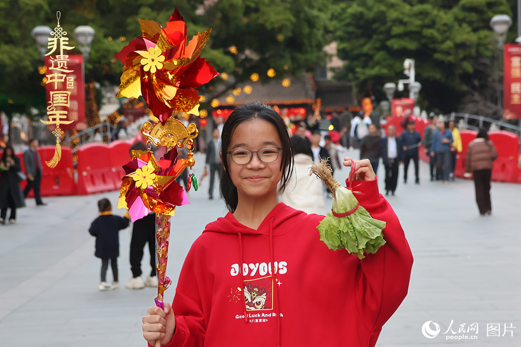 2025年2月11日，广东省佛山市禅城区，小朋友手持风车和生菜等寓意吉祥的物品走过通济桥，祈福新年如意。人民网 何善福摄